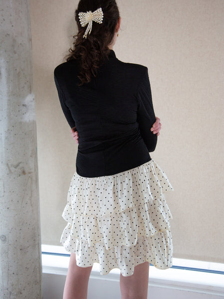 Woman wearing vintage 1980s black and white long-sleeved dress with ruffled tiered skirt