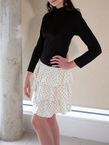 Woman wearing vintage 1980s black and white long-sleeved dress with ruffled tiered skirt