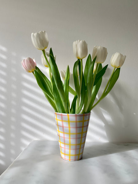 A vintage ceramic vase with hand-painted pink and yellow gingham design on a white glaze