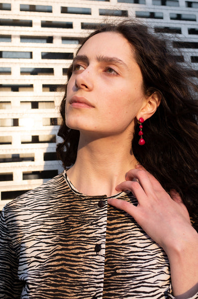 Rosalind Jana wears magenta beaded drop earrings and tiger-stripe cardigan by Human Sea Vintage
