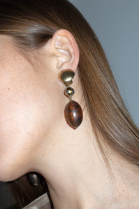 Model wears amber resin drop earrings with clip-on fastening