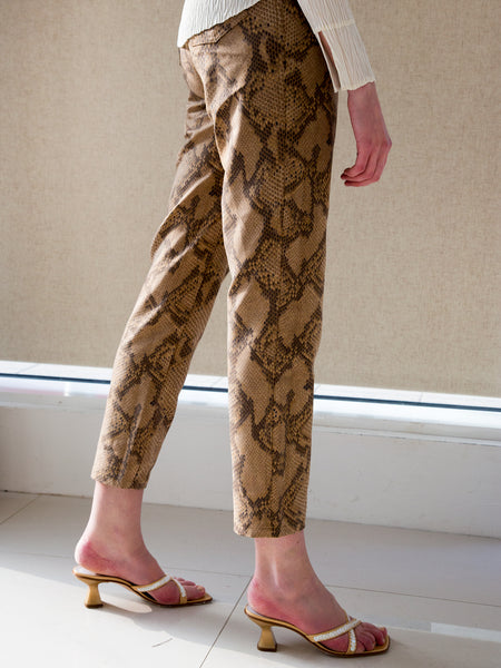 Woman wearing snake-print jeans with gold sequinned minimalist mules